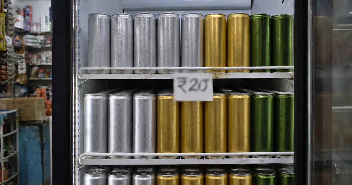 Unlabeled slim beverage cans in an Indian kirana fridge, illustrating caffeinated drinks sold as energy drinks